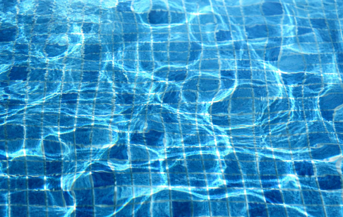 Sunlight caustics rippling across clear blue pool tile